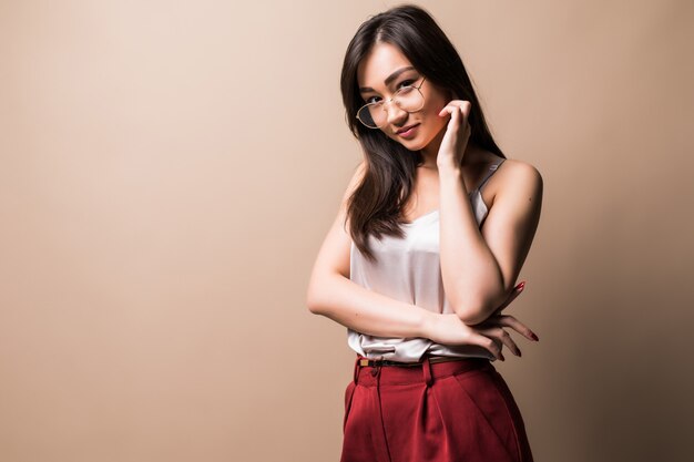 charming asian woman standing isolated over beige wall