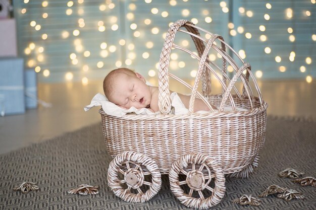 Charming baby sleeping in wicker stroller cream