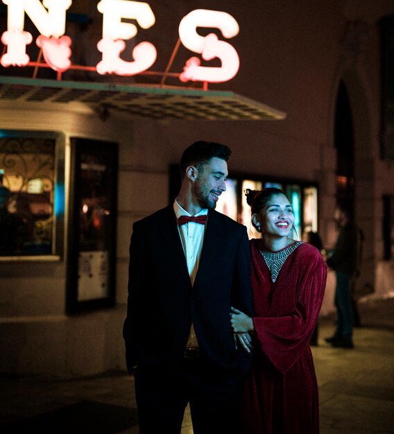 Charming beautiful smiling lady walking with young guy on street at night 