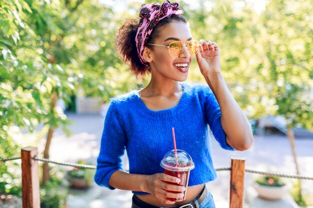 Charming  black woman with stylish  hairstyle with headband spending her weekend in the park