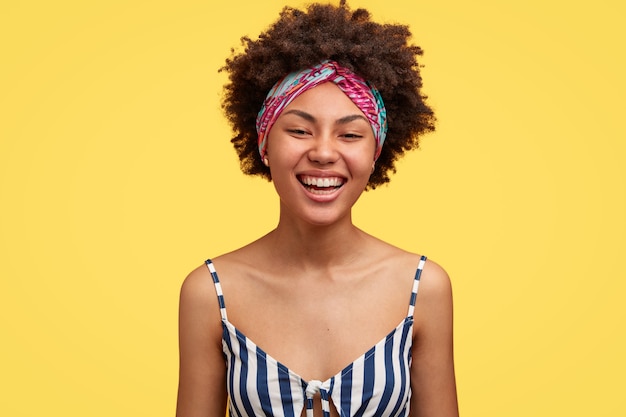 Affascinante giovane donna nera con taglio di capelli afro sorride positivamente