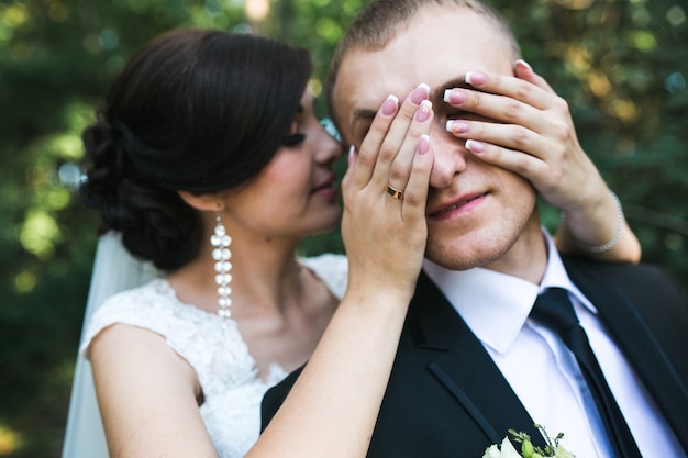 魅力的な花嫁が夫に目を閉じる（後ろから）