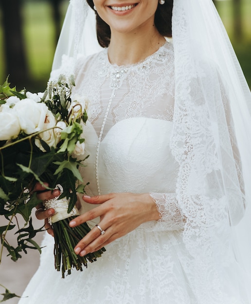 Charming bride with classy bouquet stands outside