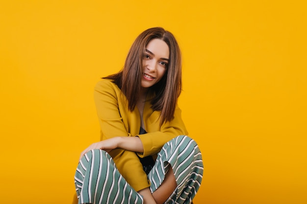 Charming brown-eyed caucasian girl sitting. Photo of carefree woman with straight hairstyle posing.