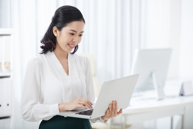 Charming ethnic businesswoman using laptop