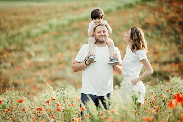 Charming family stand among the poppies field