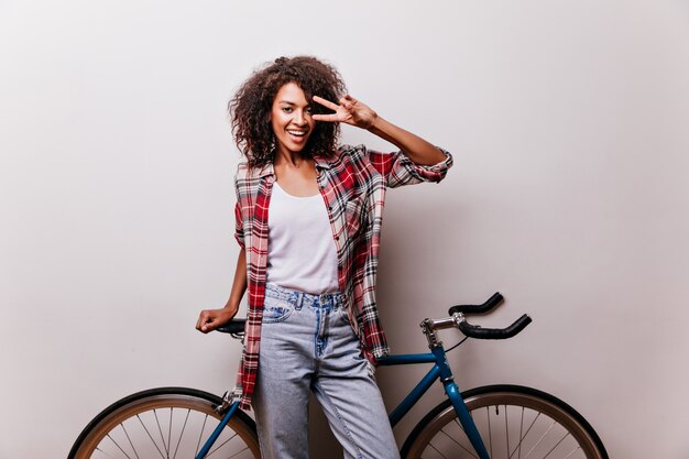 체크 무늬 셔츠 웃음에 매력적인 여성 자전거. 자전거와 함께 포즈를 취하고 행복을 표현하는 기분 좋은 여자.