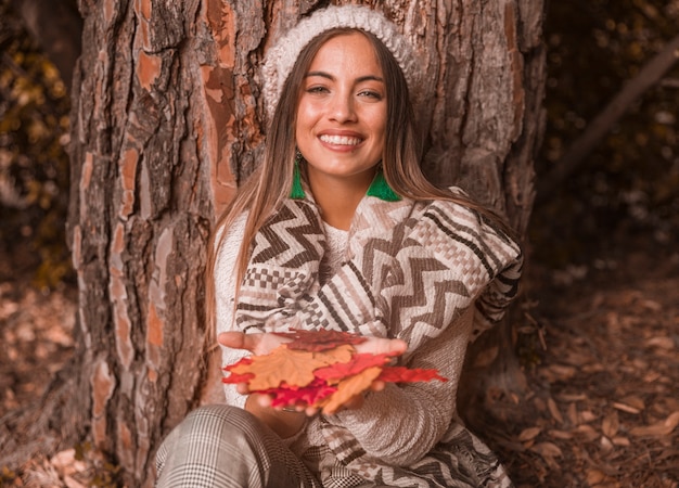 Charming female with autumn leaves near tree