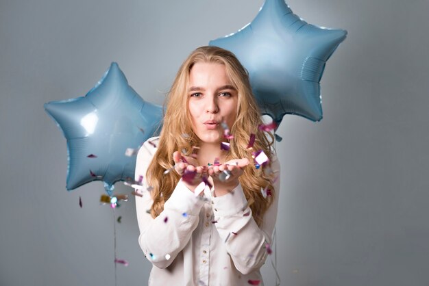 Charming female with balloons blowing at confetti