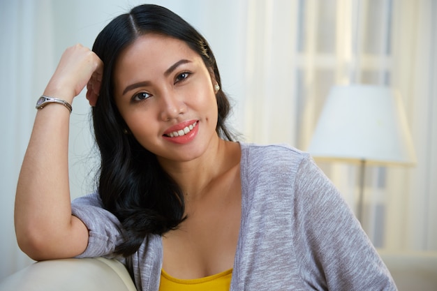 Charming Filipino woman leaning on sofa back