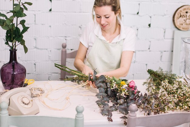 Charming florist tying ribbon on bouquet