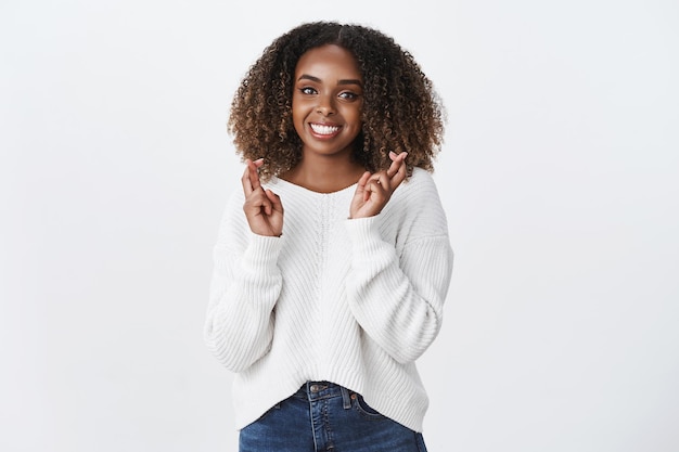 Charming friendly good-looking african american curly-haired woman praying for good luck