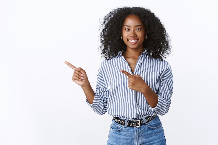 Free Photo charming friendly-looking smiling african-american assistant help you make choice grinning pleasant pointing left index finger promoting copy space product, standing joyfully upbeat white wall