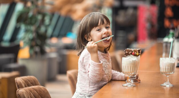 Очаровательная смешная маленькая девочка пьет молочный коктейль