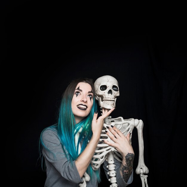 Charming girl embracing toy skeleton