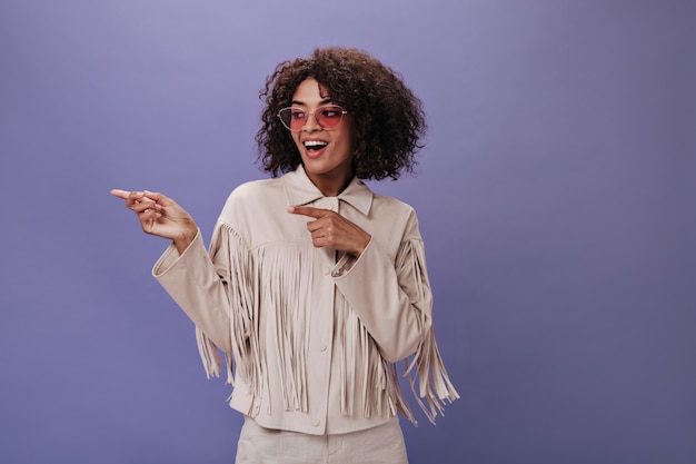 Free photo charming girl in jacket with fringe and glasses shows finger to side