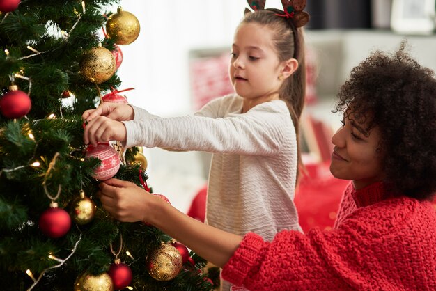 クリスマスツリーを飾る魅力的な女の子とお母さん