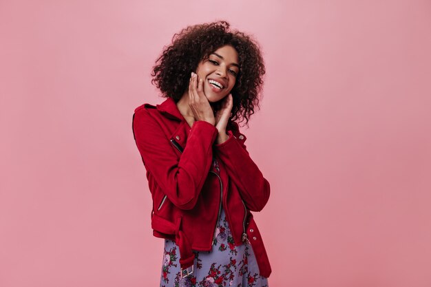 Charming girl in red jacket laughs on pink wall