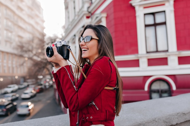 Charming girl with long straight hair taking picture of town