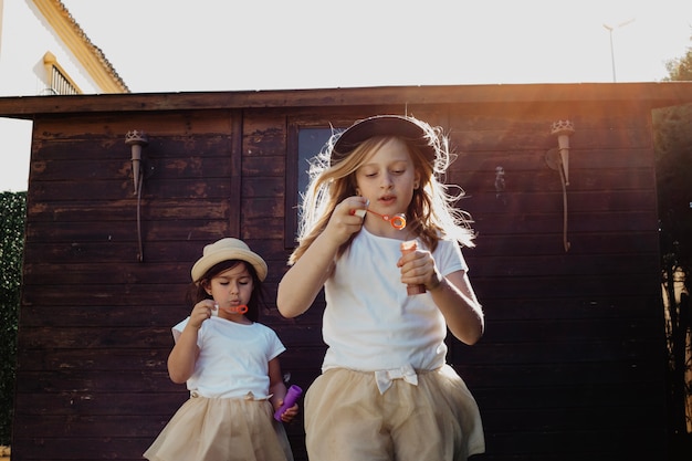 Charming girls in hats blowing bubbles