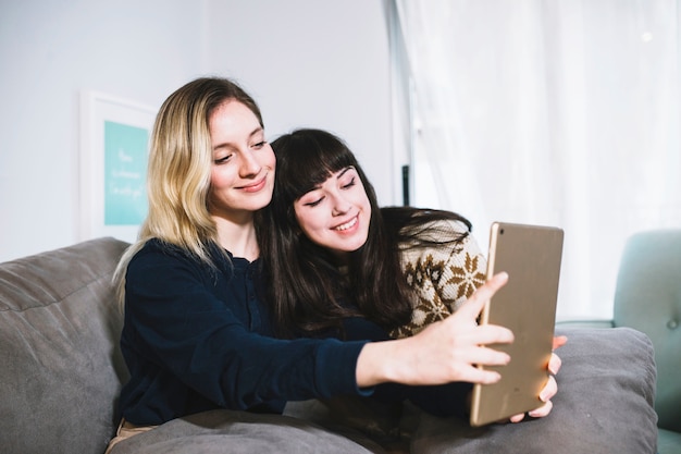 Charming girls taking selfie with tablet