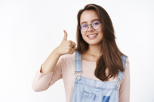 Charming happy and delighted female freelancer assuring work done in time showing thumbs up