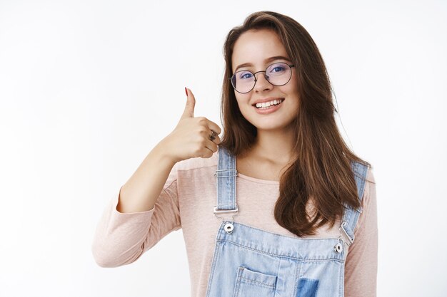 엄지손가락을 치켜세워 제 시간에 완료되는 작업을 보장하는 매력적인 행복하고 즐거운 여성 프리랜서