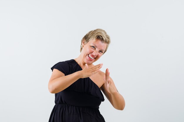 Charming lady in black blouse showing small size gesture and looking glad 
