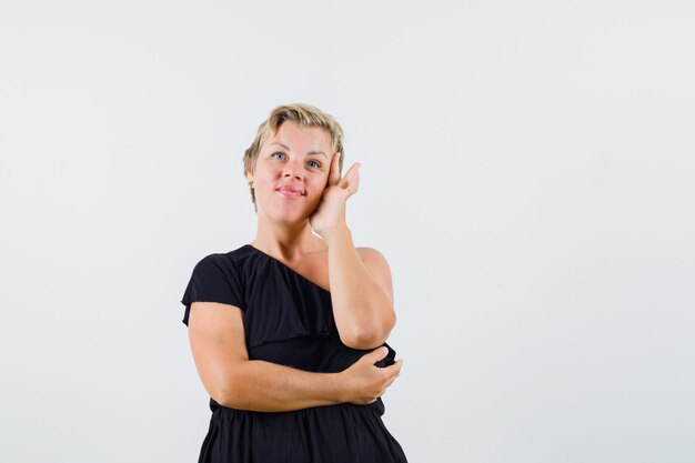 Charming lady holding hand on her face in black blouse 