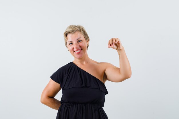 Charming lady holding something in black blouse and looking merry 