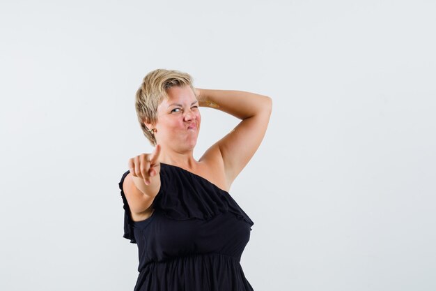 Charming lady pointing at camera while winking in black blouse 