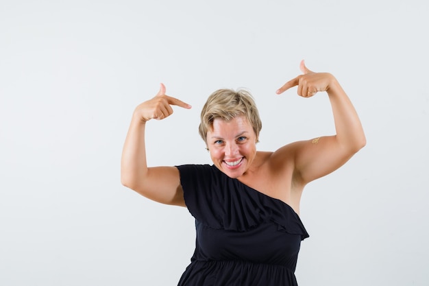 Free photo charming lady pointing at her head in black blouse and looking optimistic