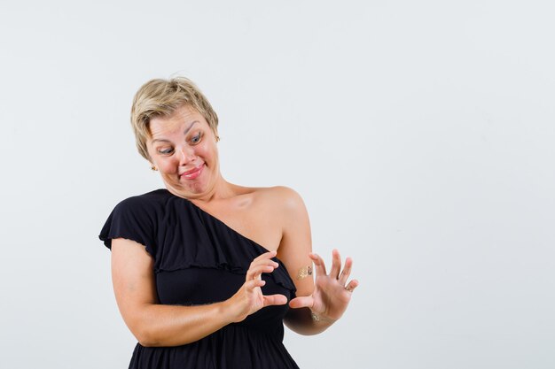 Charming lady posing like holding something in black blouse 