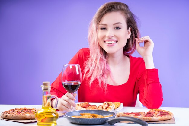 Charming lady in red blouse sitting at the table with glass of wine
