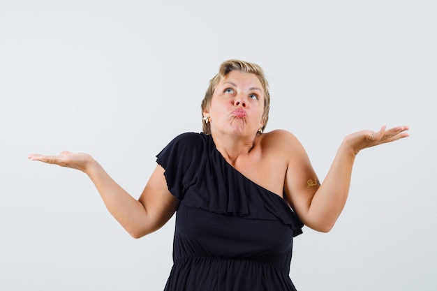 Charming lady showing helpless gesture in black blouse front view.