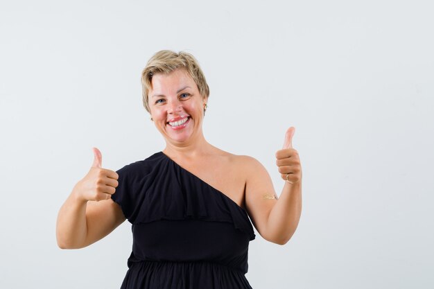 Charming lady showing thumb up in black blouse and looking satisfied. front view.