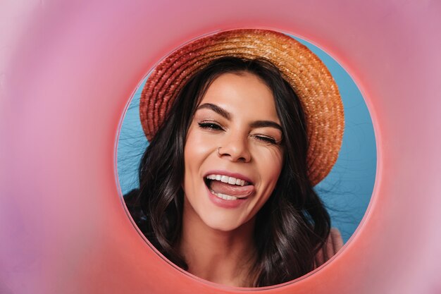 Charming lady in straw hat posing with tongue out