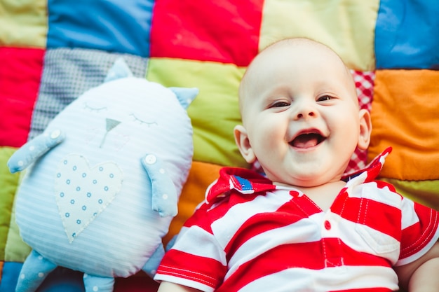 Charming little boy in red stripped shirt lies on the blanket