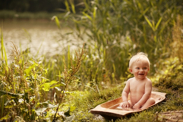 Free photo charming little boy takes a bath on the lawn in green summer park