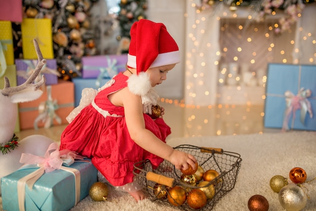 Charming little girl plays with Christmas tree toys