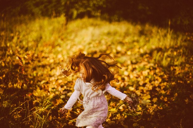 Charming little girl runs in tall autumn grass 