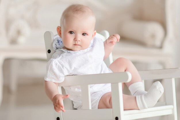 Charming newborn boy sits on the chair in the studio