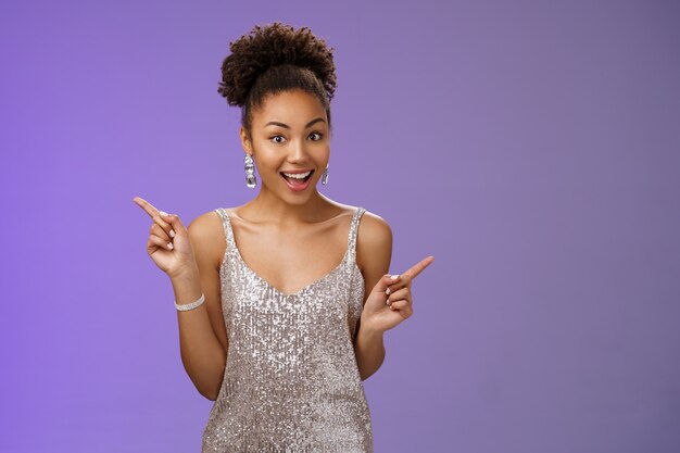 Charming outgoing african-american party girl have fun dancing pointing different sides right left show choices variants smiling broadly asking advice which way go, standing blue background.