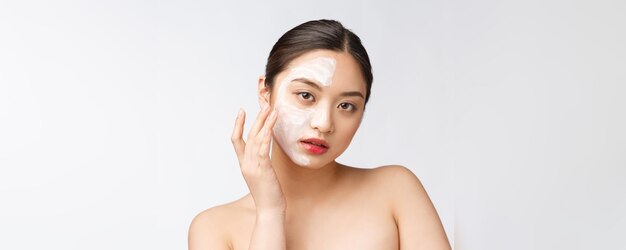 Charming pleasant woman applying cream on half face