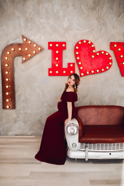 Free photo charming pregnant woman in marsala dress posing on steps of house