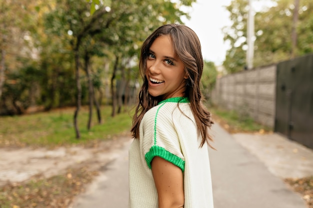 Affascinante bella donna con un sorriso meraviglioso si gira mentre cammina per la città