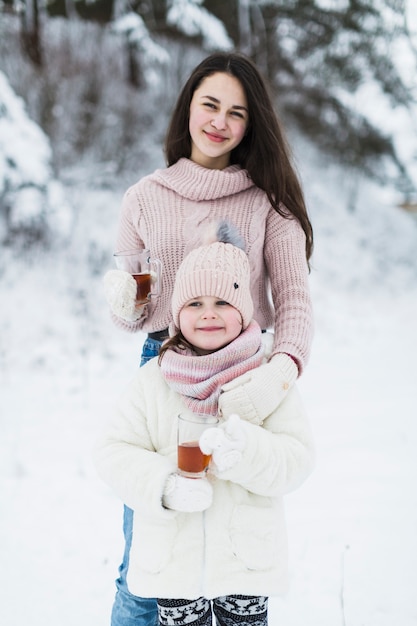 Charming sisters with tea posing for camera