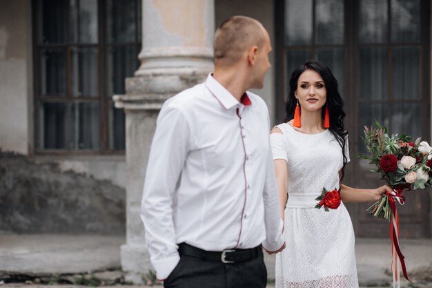 Charming and stylish wedding couple poses before a building of an old castle