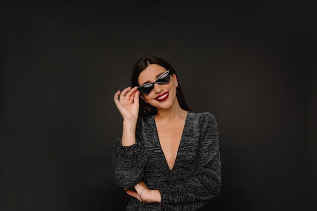 Charming stylish woman with red lips holding her glasses and smiles