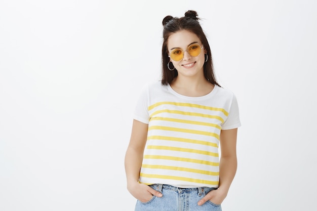 Charming stylish young woman posing against white wall